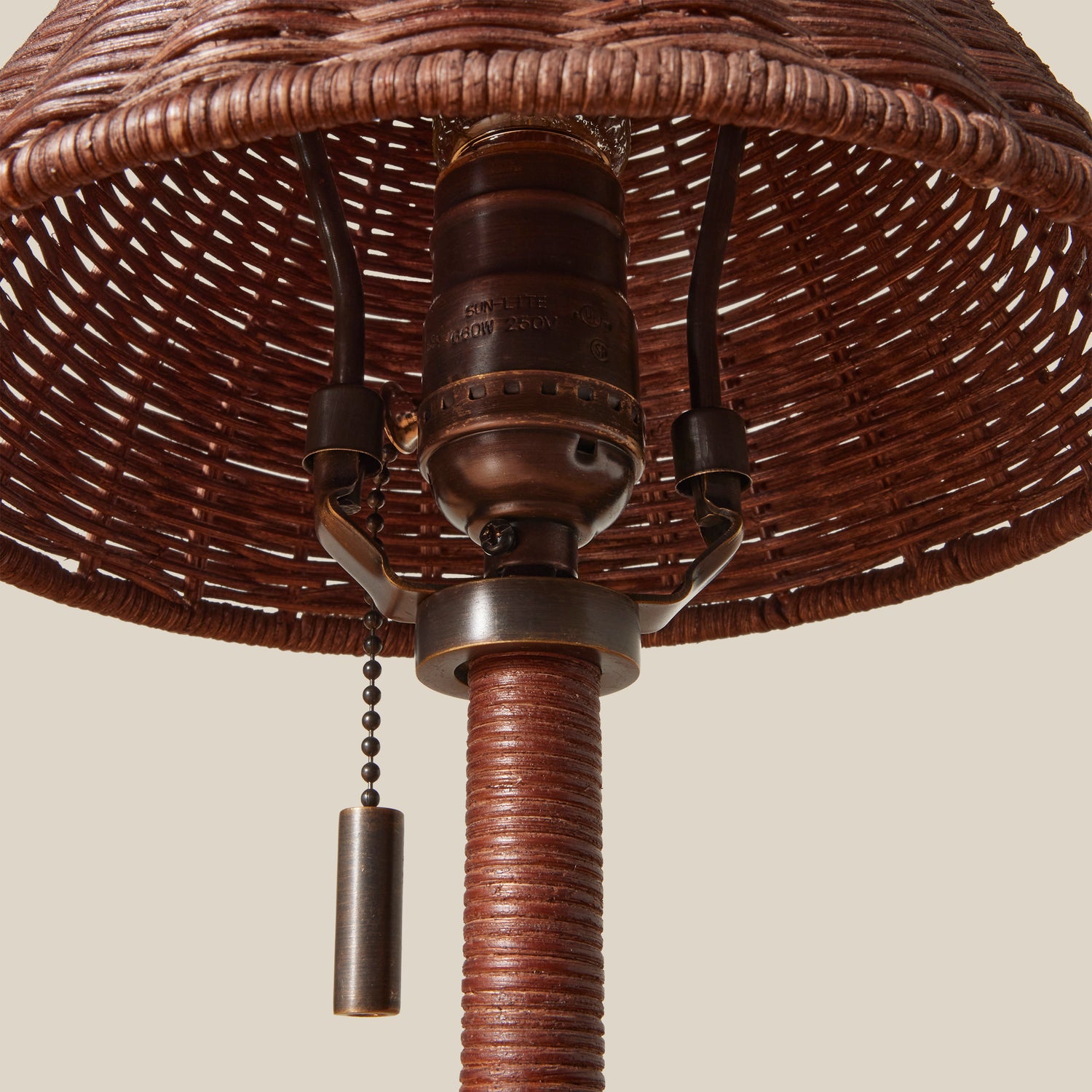 Close-up of a wicker lampshade with a metal pull chain on a beige background- Number 5