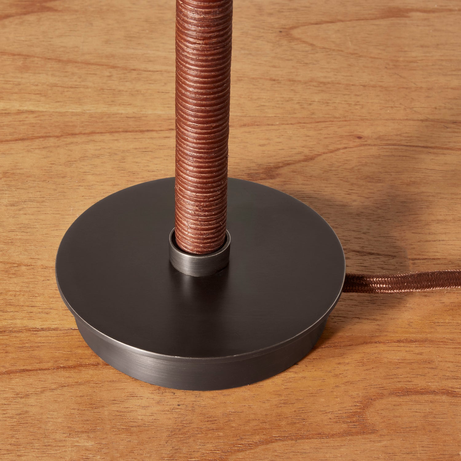 Base of a lamp with coiled brown wire on a wooden surface- Number 6
