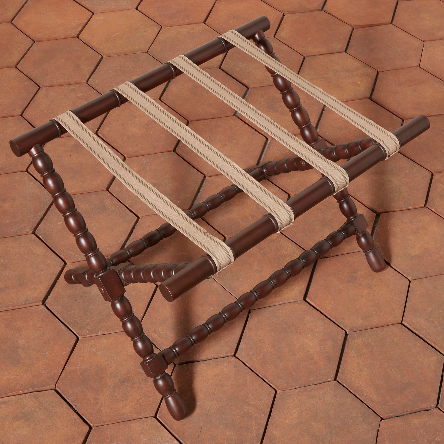 Wooden luggage rack with beige straps on a hexagonal tile floor- Number 4