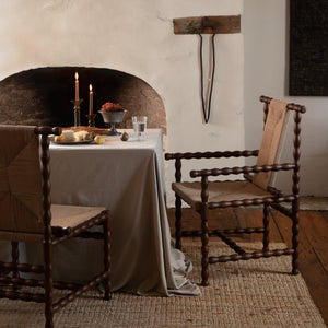 Dining room with rustic fireplace, wooden chairs, and a table set for a meal. - Number 2