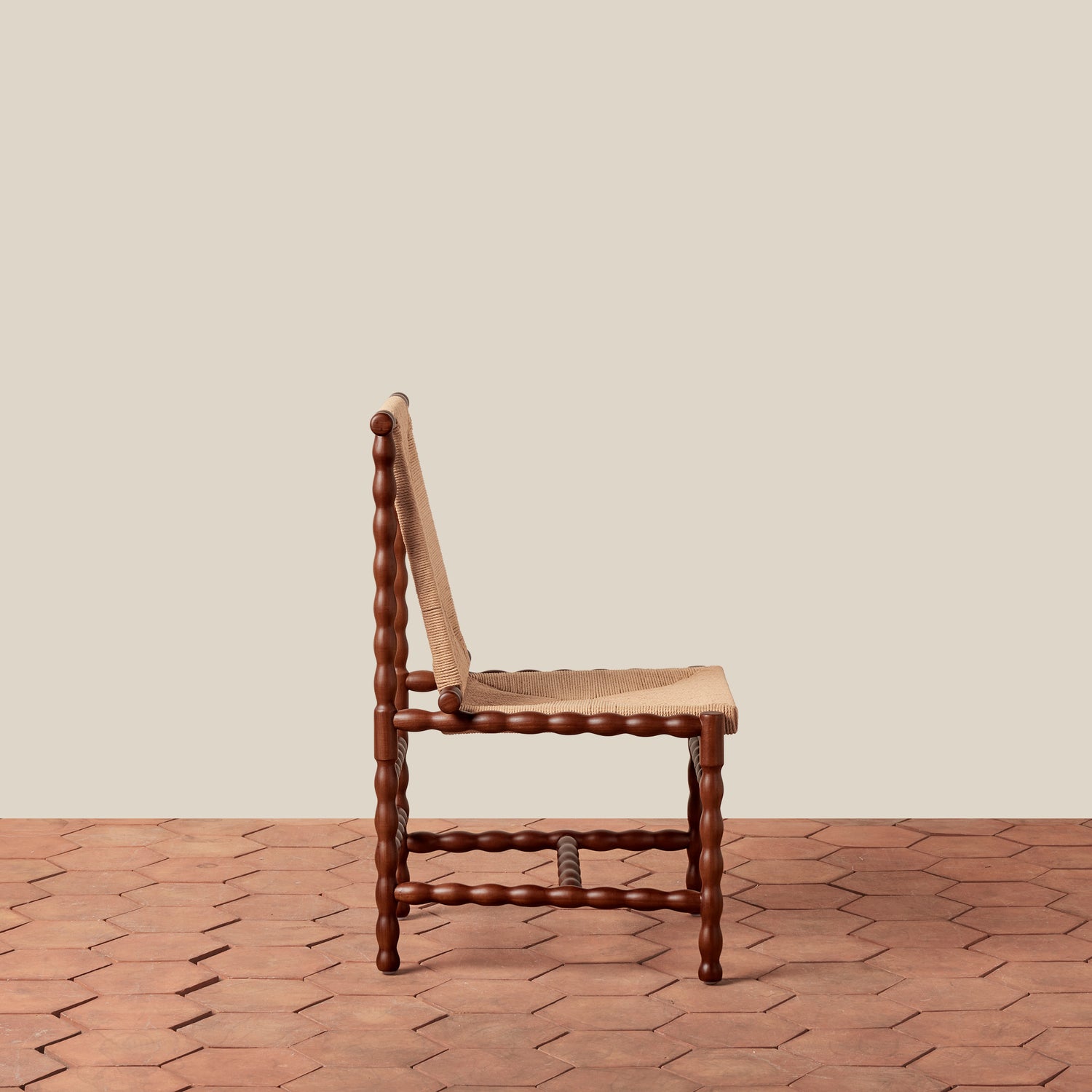 Wooden chair with woven seat on a herringbone wooden floor against a beige wall- Number 3