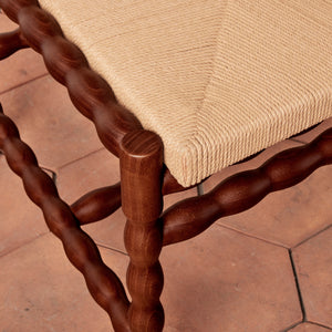 Close-up of a wooden chair with twisted legs on a tiled floor. - Number 7