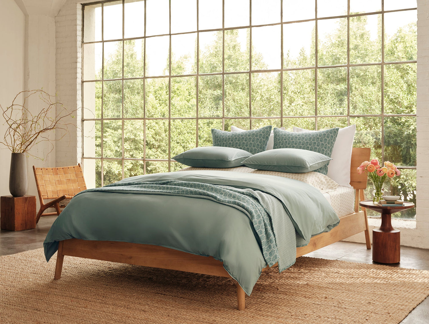 Bedroom with wooden bed, green bedding, and large windows.- Number 4