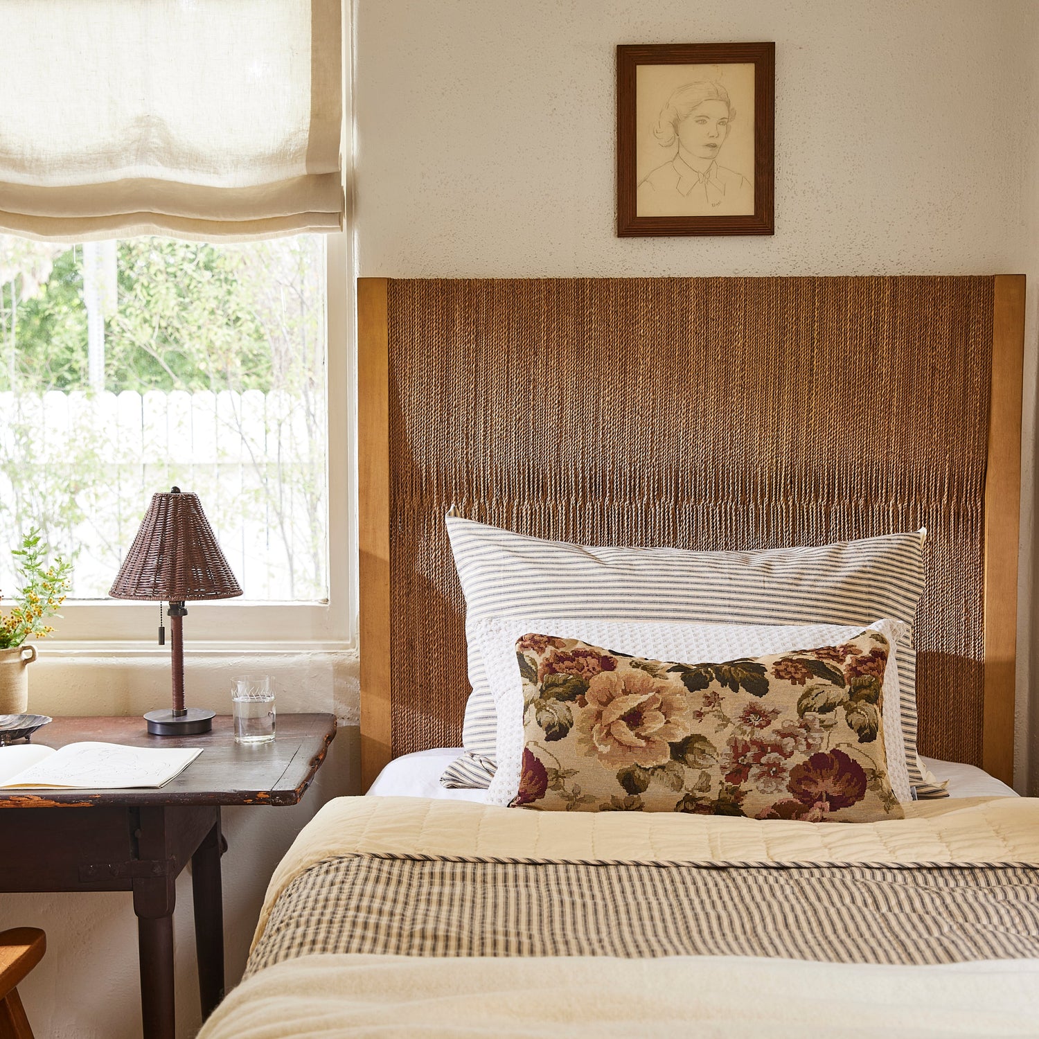 Bedroom with wooden headboard, floral pillow, and lamp on a nightstand.- Number 2