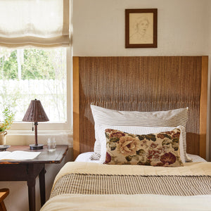 Bedroom with wooden headboard, floral pillow, and lamp on a nightstand. - Number 2