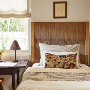 Bedroom with wooden headboard, floral pillow, and lamp on a nightstand. - Number 2