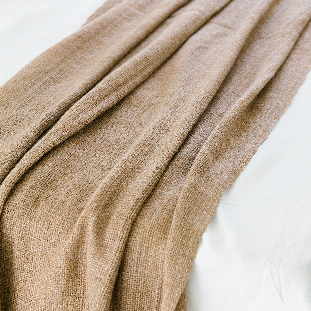 Close-up of a beige blanket draped over a white surface- Number 3