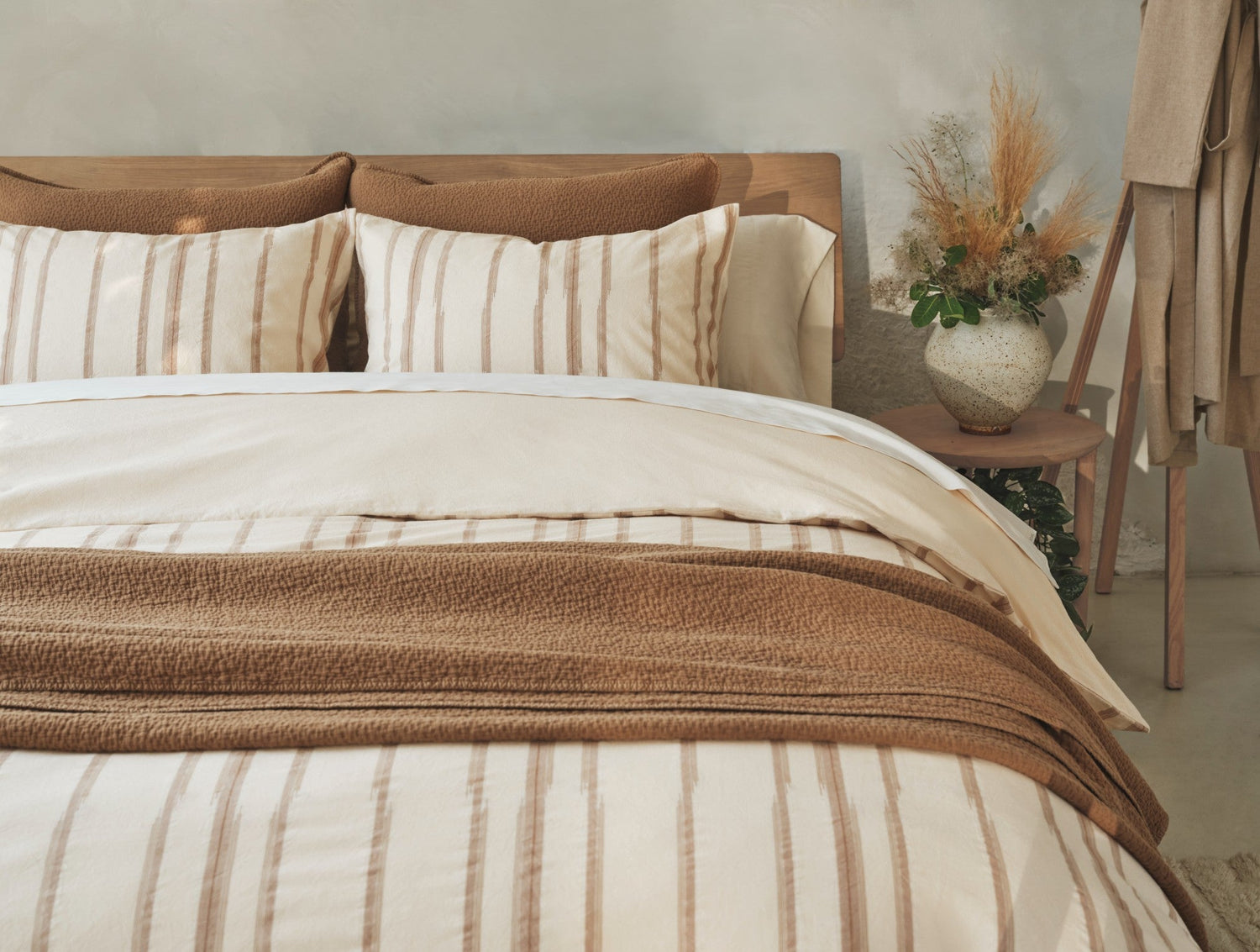 Neatly made bed with striped bedding and pillows in a bedroom setting.- Number 3