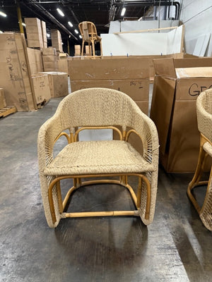 Woven chair in a warehouse setting with cardboard boxes and other furniture. - Number 2