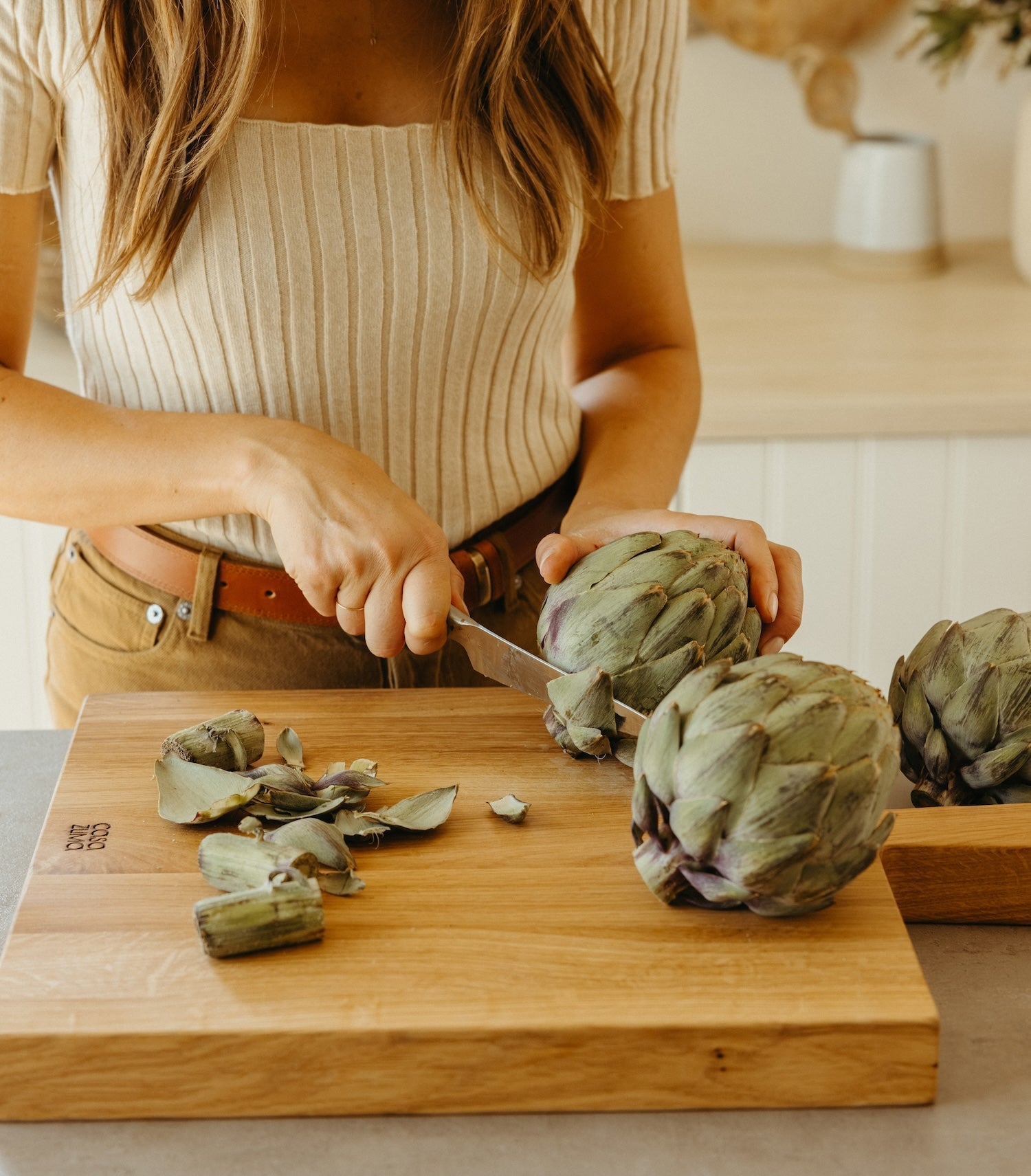 woman cutting an artichoke on cutting board- Number 3