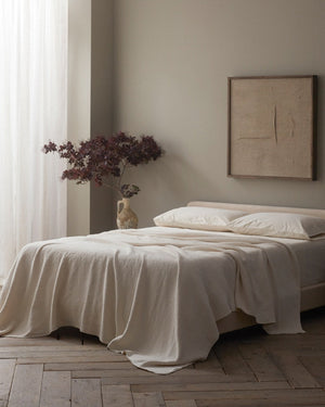 Neatly made bed in a bedroom with a plant and framed artwork on the wall. - Number 3