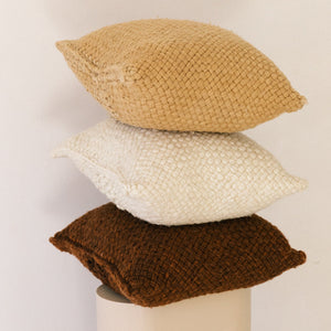 Three woven pillows in beige, white, and brown stacked on a white background - Number 3