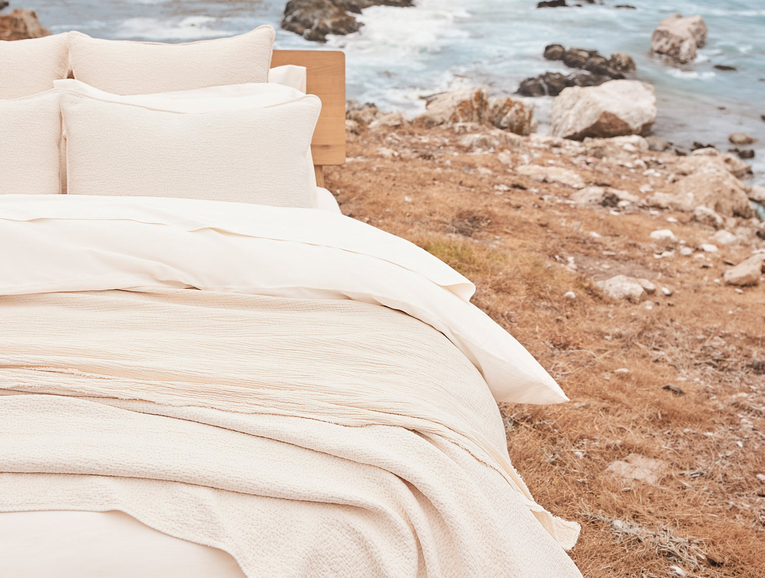 Beige bedding set on a bed with a scenic ocean view in the background- Number 2