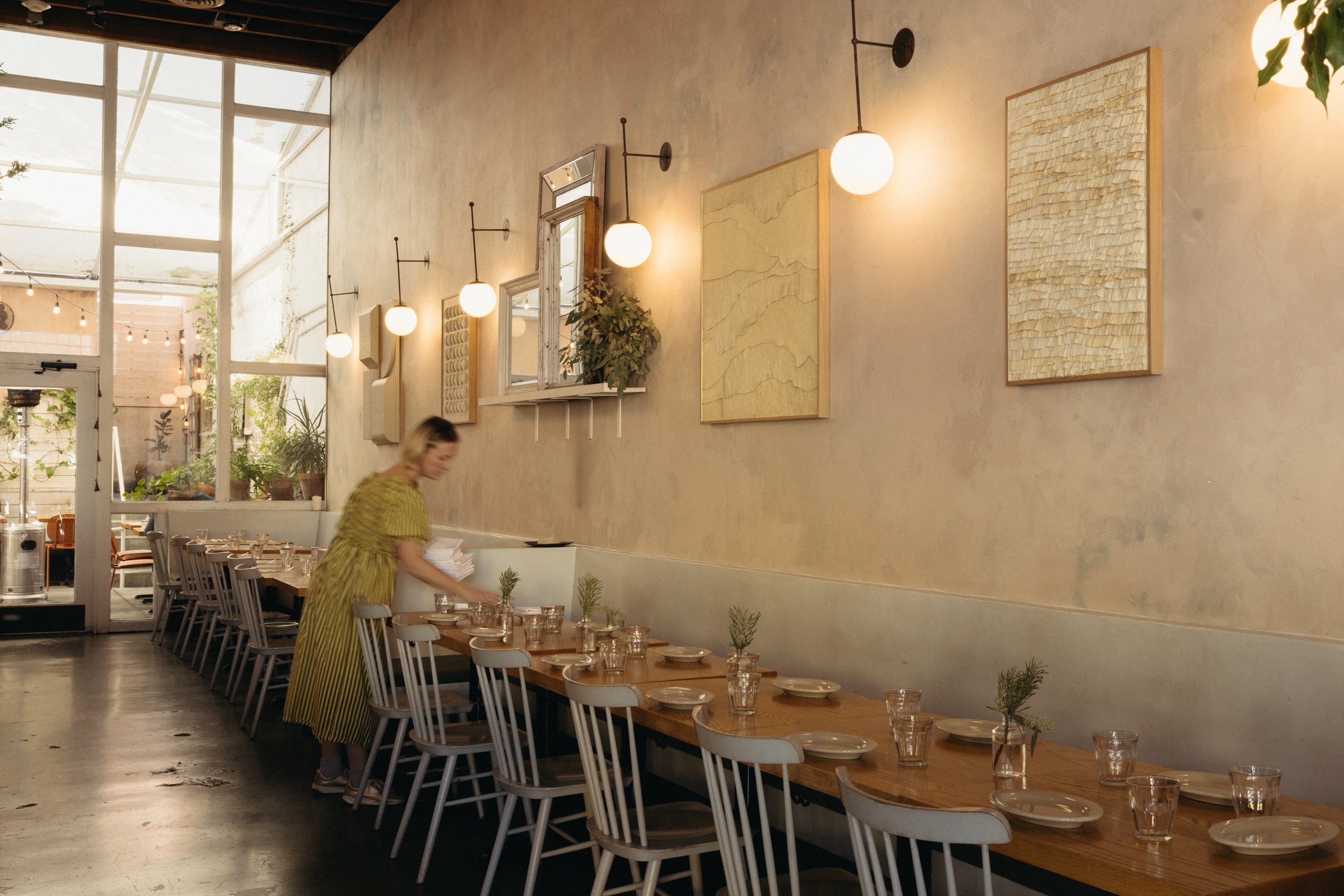 Dining area with long wooden table set for a meal, chairs, and decorative elements.