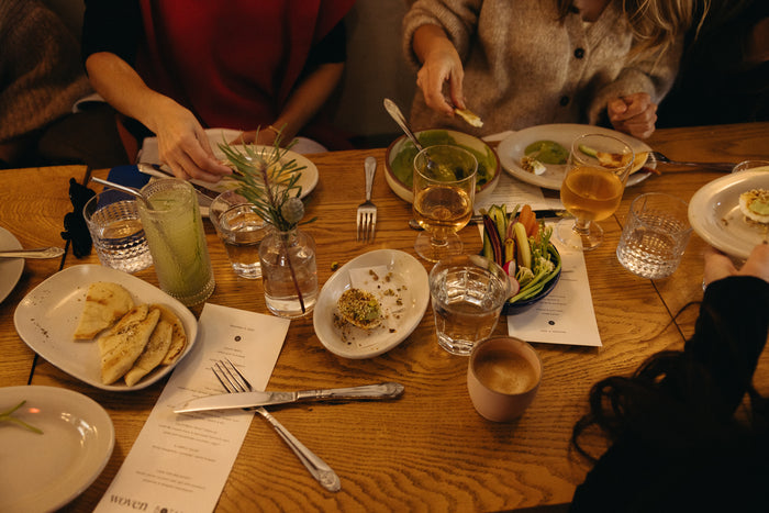 Dining table with plates, glasses, and cutlery with people around
