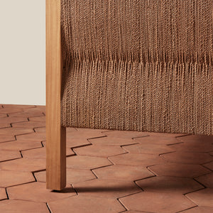 Close-up of a woven brown chair with a textured wall and patterned floor. - Number 4