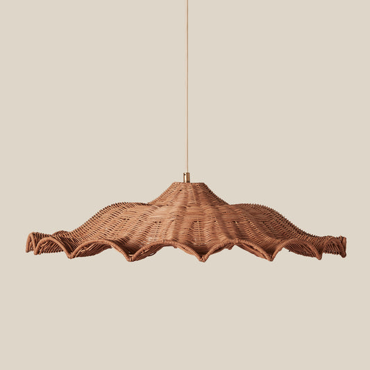 A woven wicker pendant light with a wide, scalloped shade suspended by a thin cord against a solid beige background.