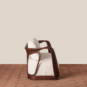 A modern accent chair with a dark brown wicker frame and plush off-white textured seat and back cushions, set against a minimalist beige wall and brown patterned tile floor. - Number 5