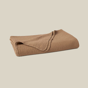 A folded brown fleece blanket with a textured waffle-knit surface, shown on a solid light beige background. - Number 1