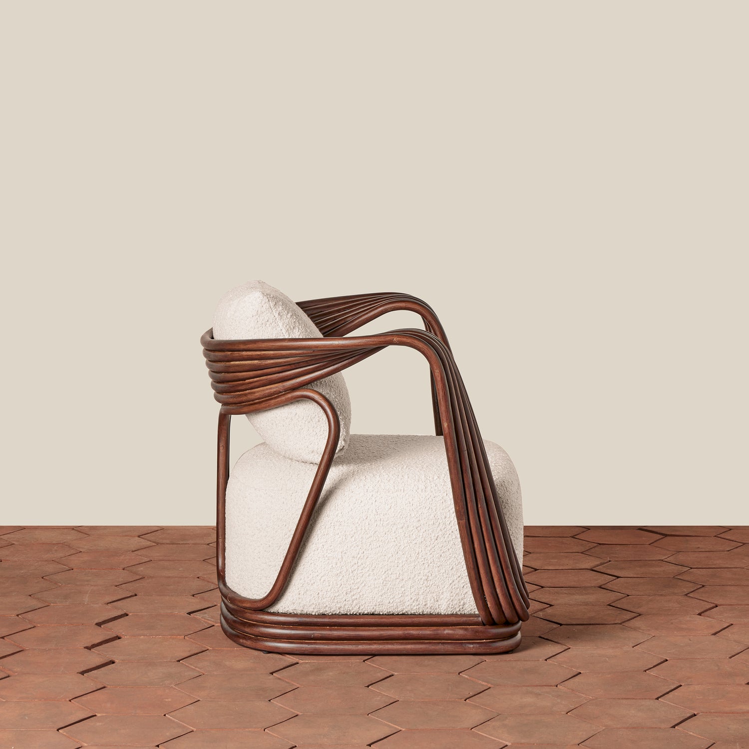 A modern armchair with a dark brown wicker frame and textured off-white bouclé cushions, set against a neutral beige wall and brown herringbone wood floor.- Number 4
