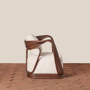 A modern armchair with a dark brown wicker frame and textured off-white bouclé cushions, set against a neutral beige wall and brown herringbone wood floor. - Number 4