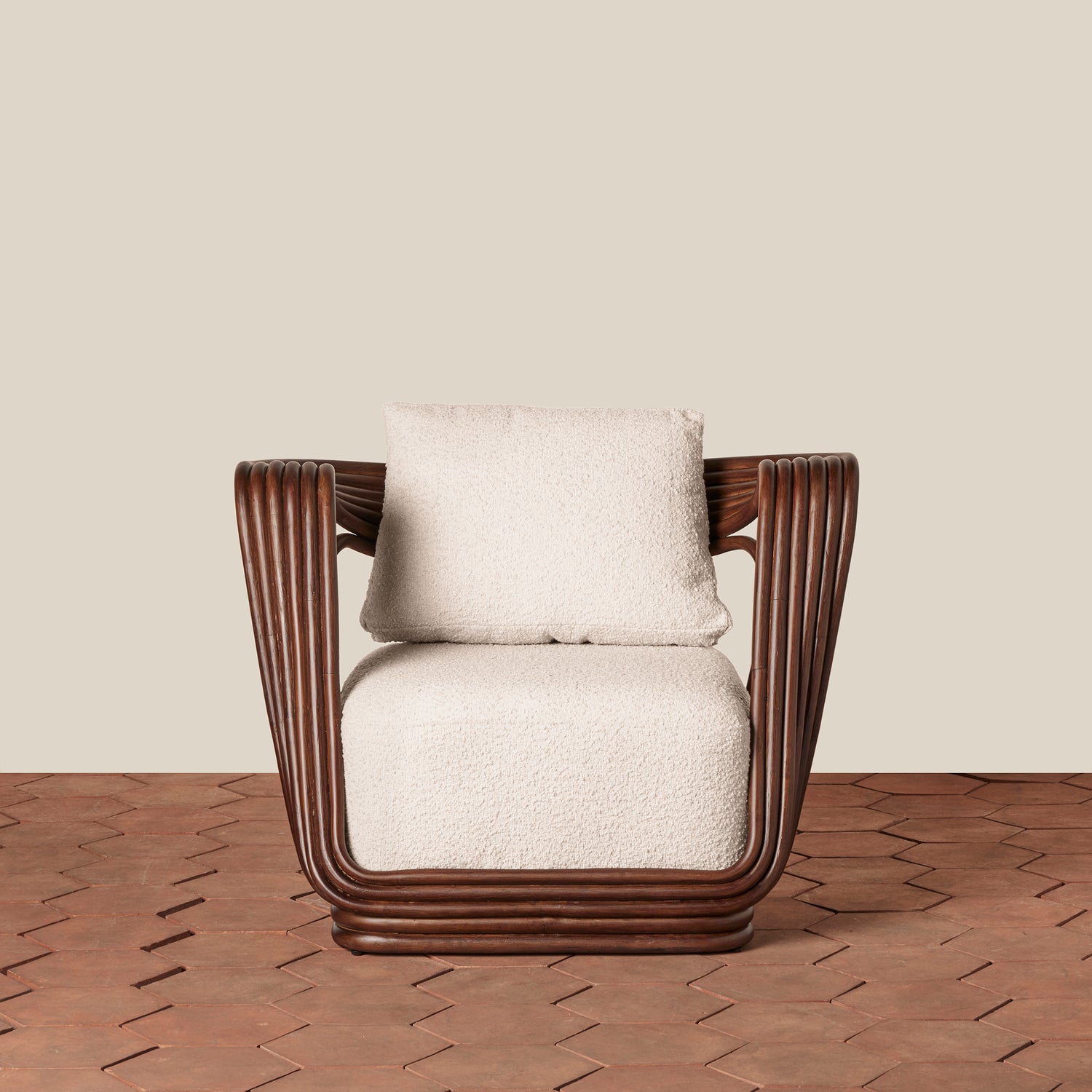 A modern accent chair with a dark brown ribbed frame and textured cream bouclé seat and back cushions, set against a neutral beige wall and brown herringbone wood floor.- Number 5