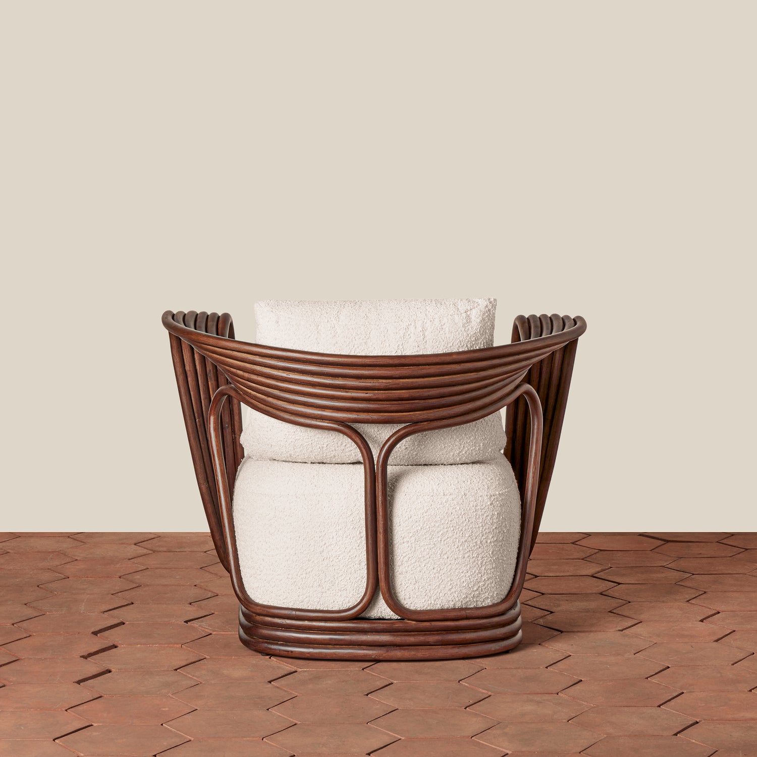 A modern accent chair with a dark brown wicker frame and textured cream boucle cushions, set against a solid beige wall and a brown herringbone wood floor.- Number 6