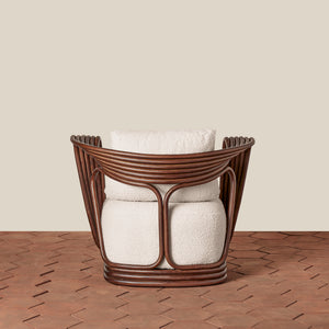 A modern accent chair with a dark brown wicker frame and textured cream boucle cushions, set against a solid beige wall and a brown herringbone wood floor. - Number 6