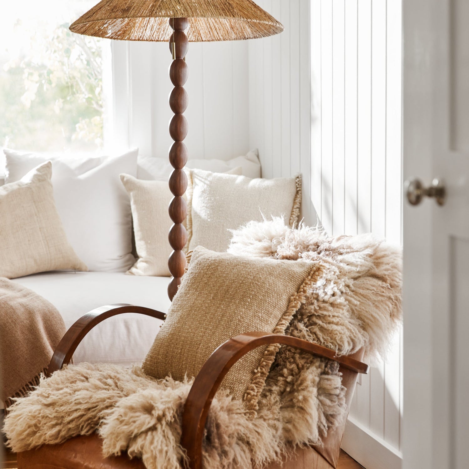 Cozy living room with a chair draped with a fluffy blanket, a lamp, and a couch with pillows.- Number 2