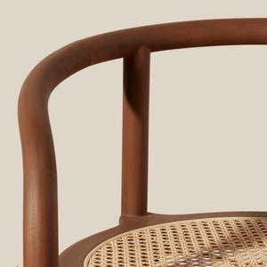 Close-up of a wooden chair showing the curved backrest, vertical support posts, and woven cane seat against a plain beige background. - Number 5