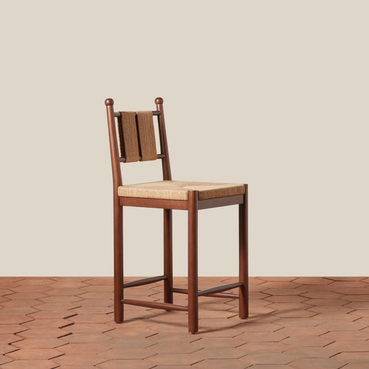 Wooden bar stool with woven backrest and seat on a wooden floor.