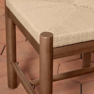 Close-up of a wooden chair with a woven rope seat in a warm beige tone, set on a terracotta tiled floor. - Number 16