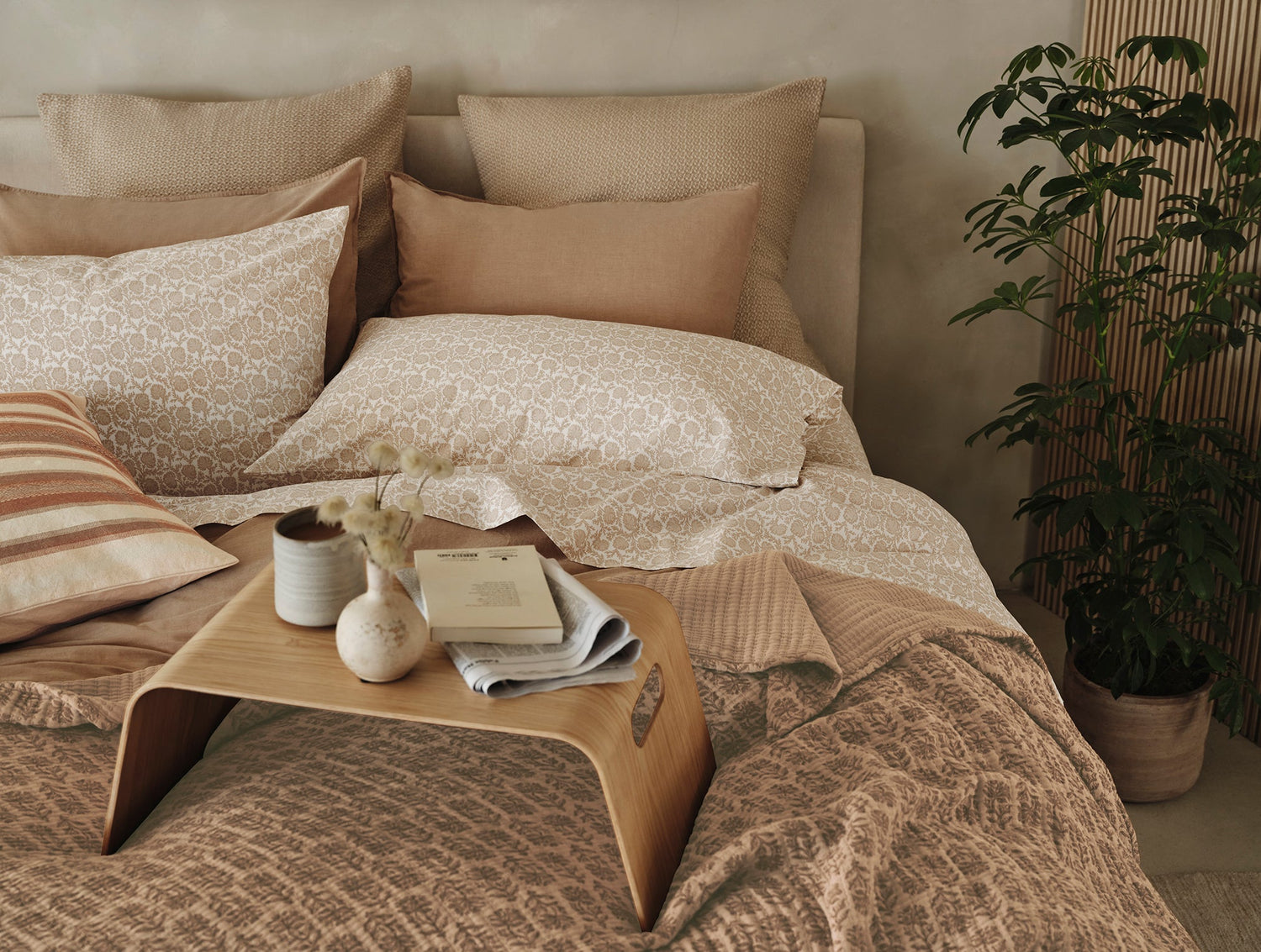 Cozy bedroom with patterned bedding, pillows, and a small table.- Number 3