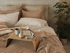 Cozy bedroom with patterned bedding, pillows, and a small table. - Number 3