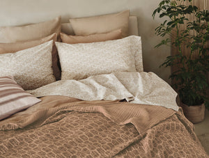 Neatly made bed with patterned bedding and pillows in a cozy room. - Number 2