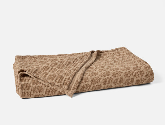 Folded brown textured blanket on a white background