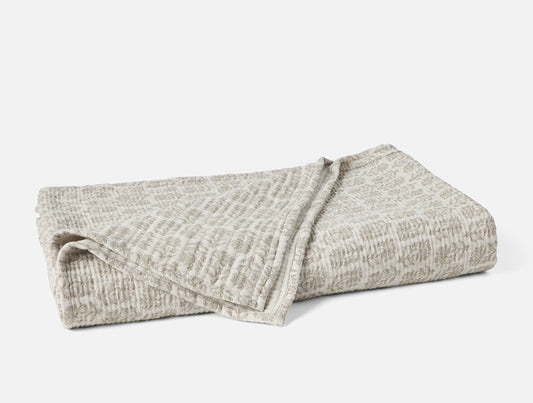 Folded beige blanket on a white background