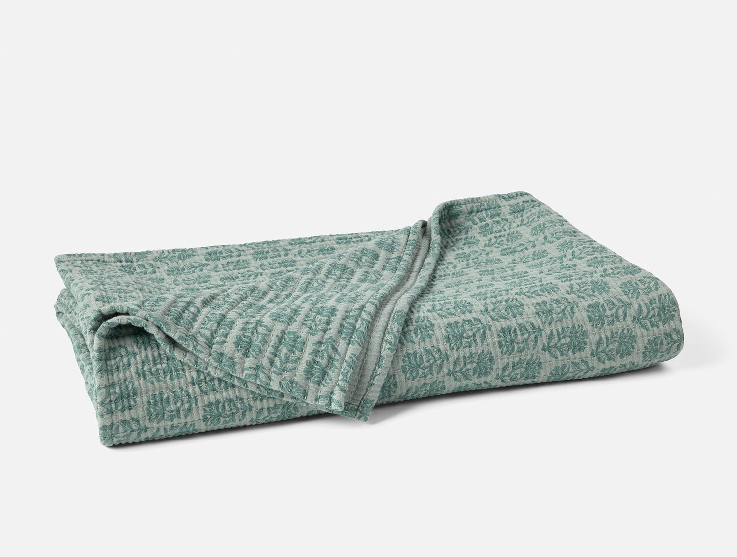 Folded green patterned blanket on a white background- Number 1