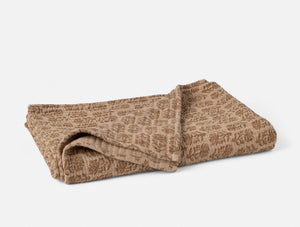 Folded brown towel with a subtle pattern on a light gray background - Number 1