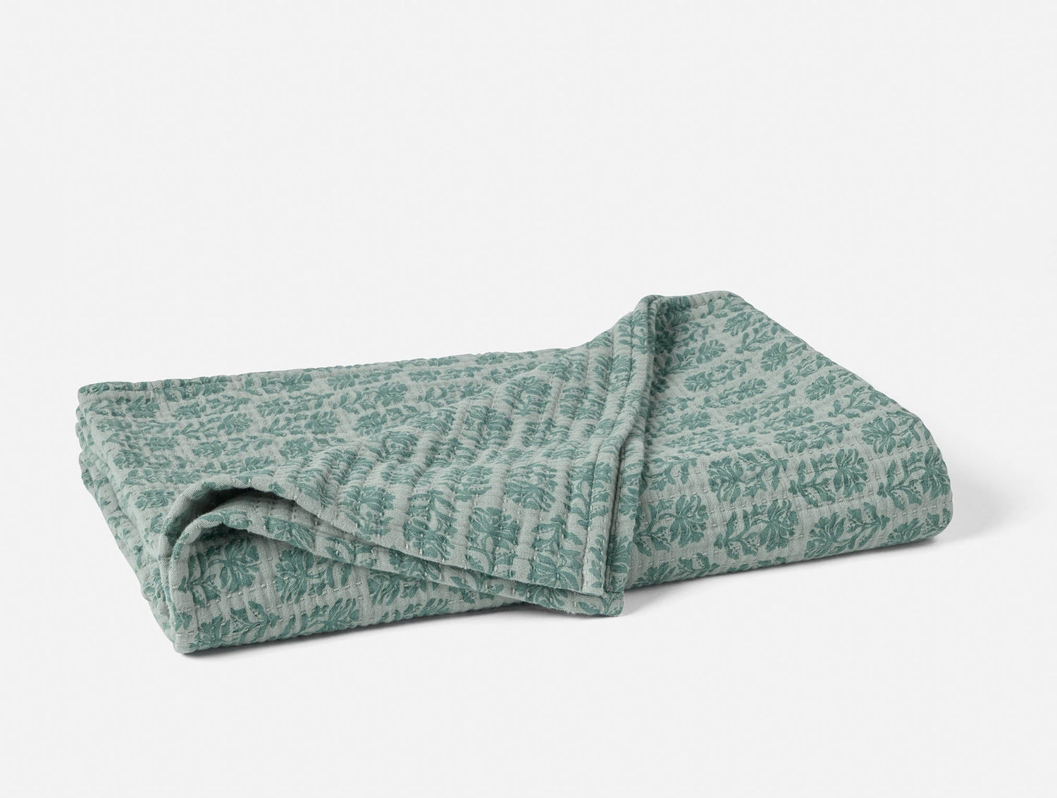 Folded green floral-patterned blanket on a white background- Number 1