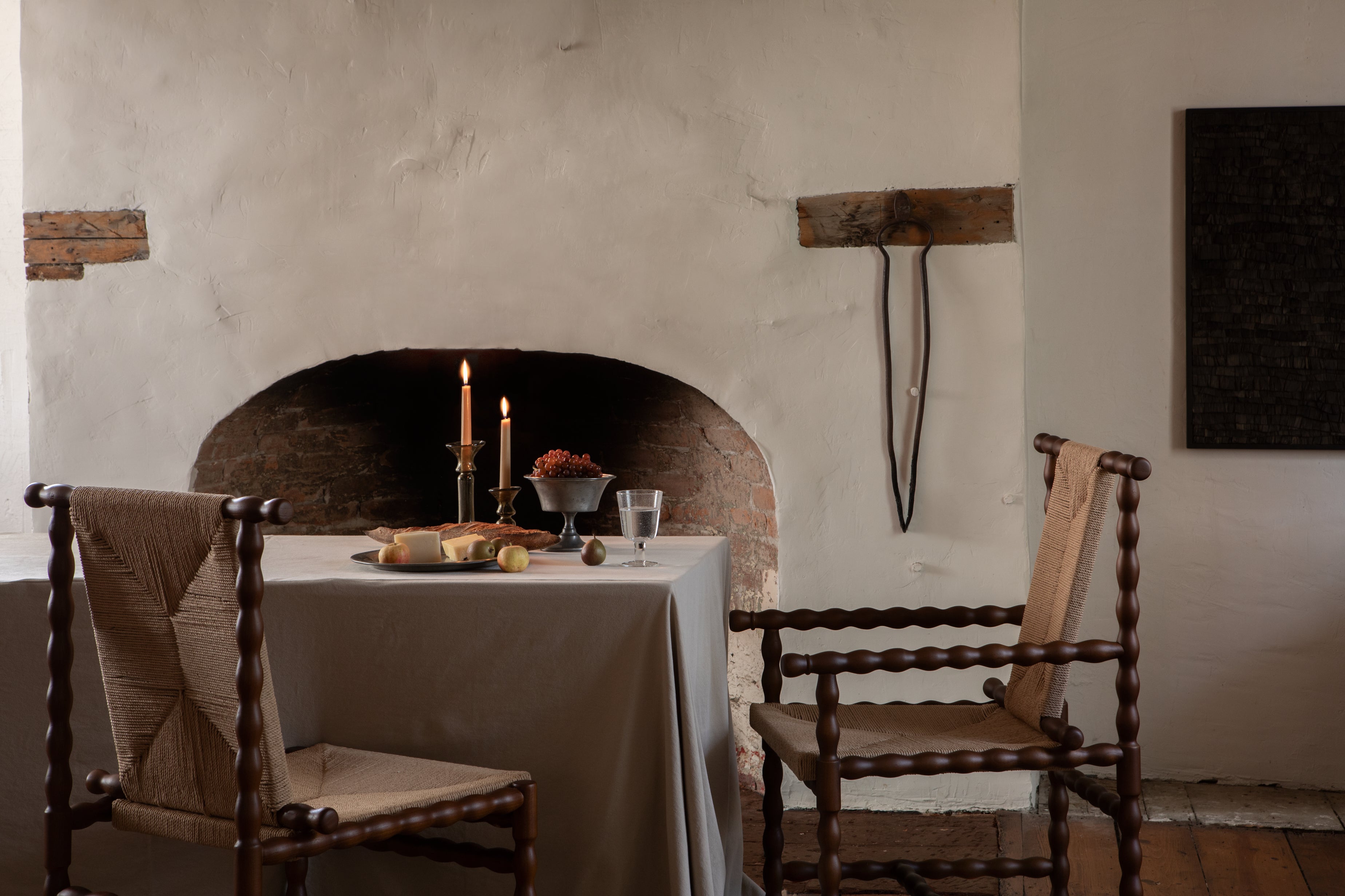 Dining area with a table set against a stone wall, featuring candles and a vase.