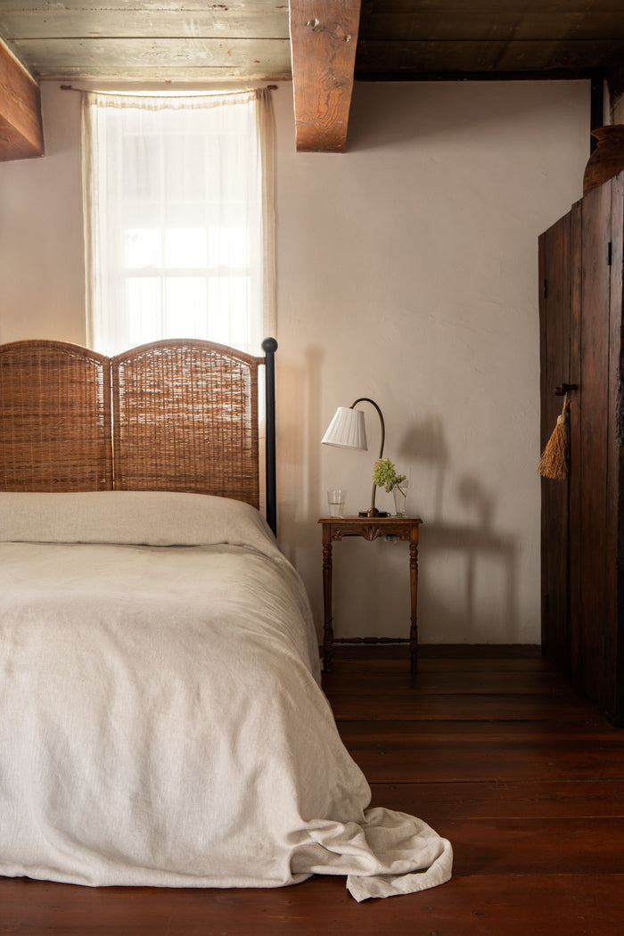 Bedroom with wooden headboard, white bedding, and side table with lamp.