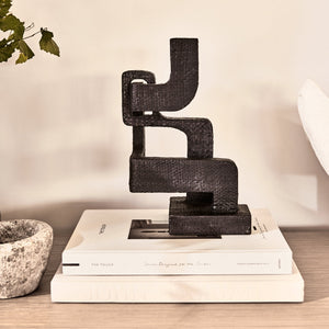 abstract black sculpture on white books, against a white wall  - Number 2