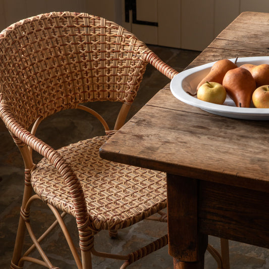 Wicker chair next to a wooden table with a plate of fruit in a kitchen. - Image 2