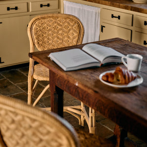 Wooden dining table with an open book, plate of food, and cup in a cozy kitchen setting. - Number 3