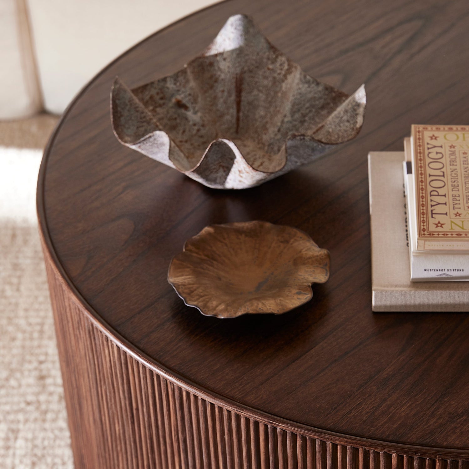 Round wooden coffee table with decorative items on a beige carpet- Number 3