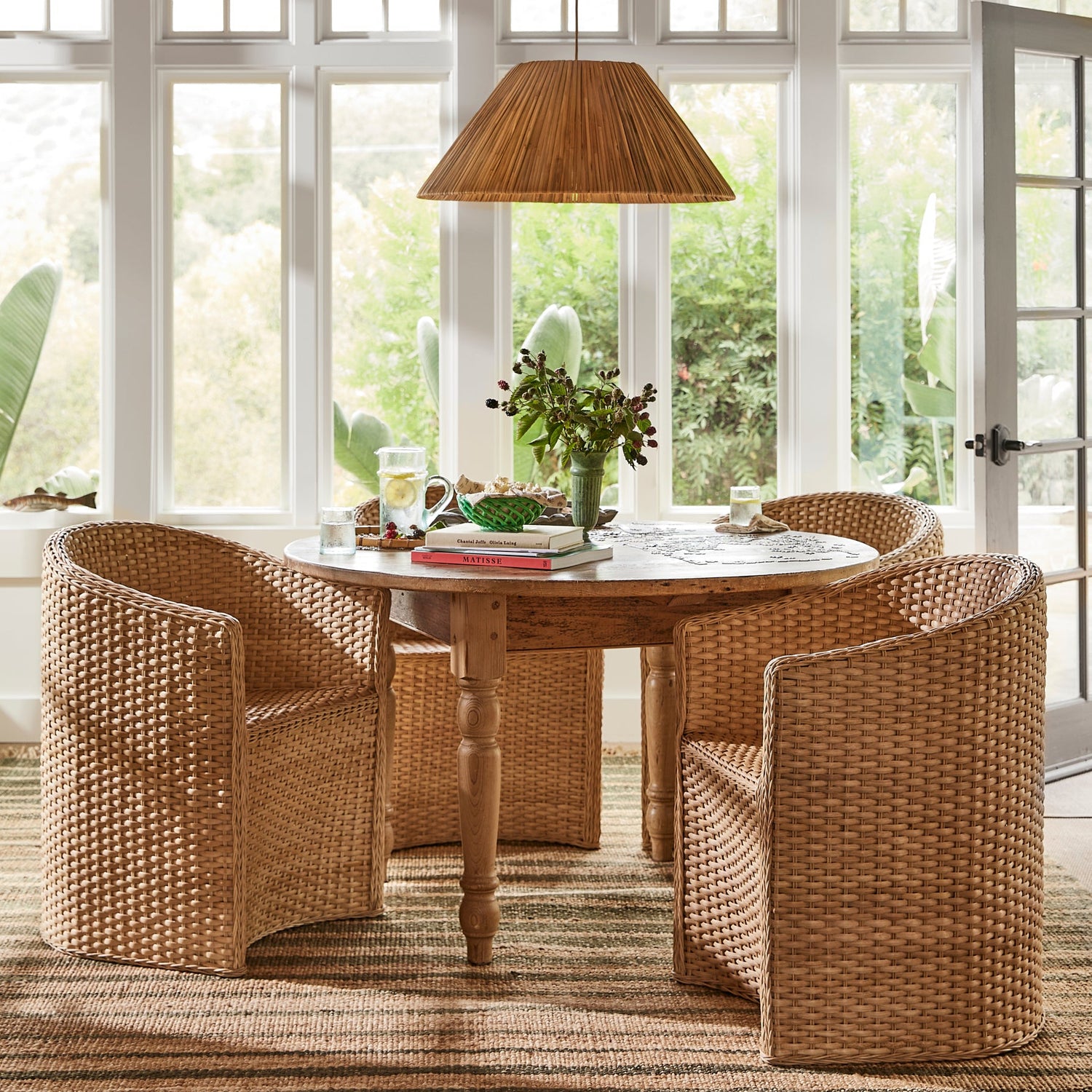 3 large chairs around circular table with pendant light hanging above, against white windows - Number 2