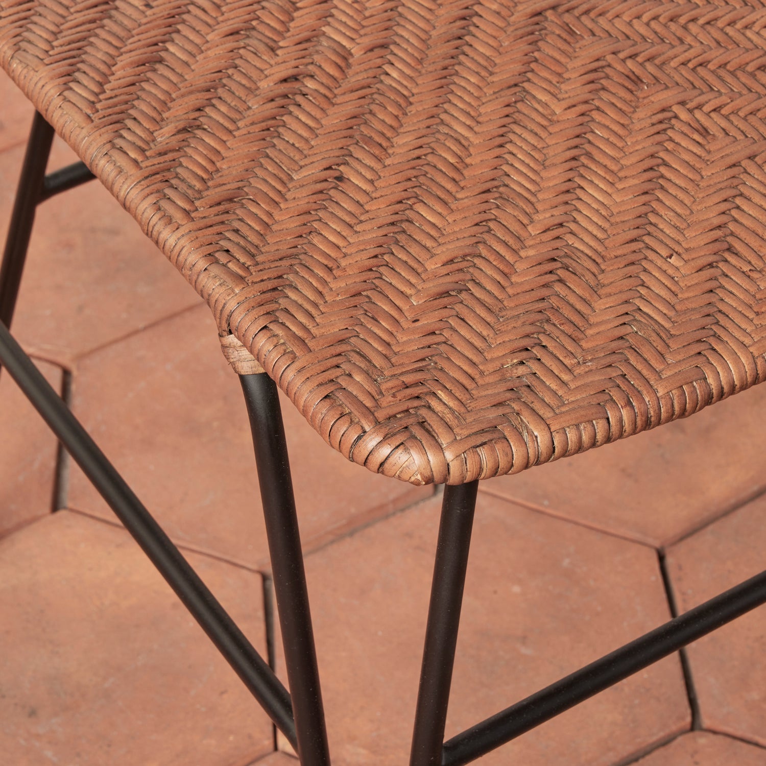 Close-up of a wicker chair with metal legs on a tiled floor.- Number 6