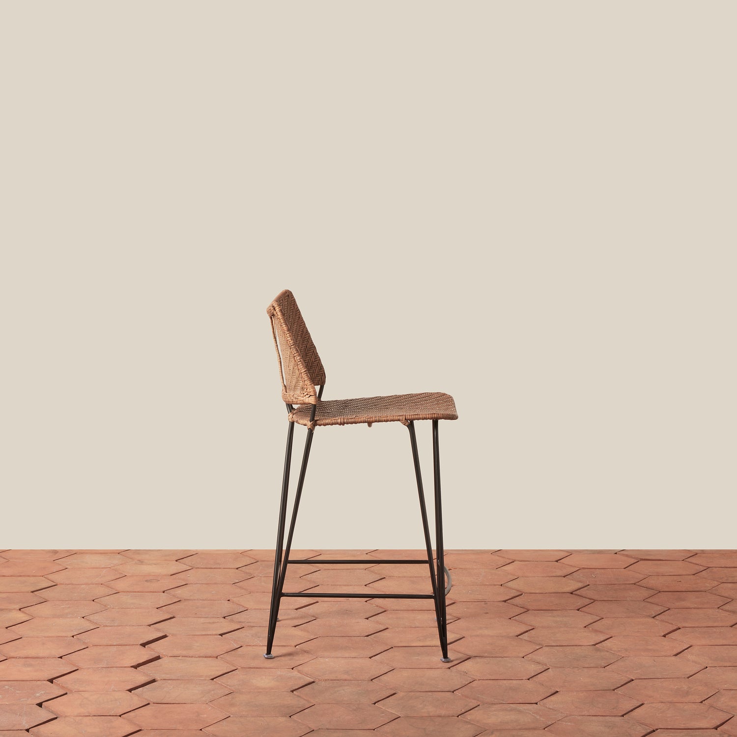 Bar stool with wicker seat and metal legs on a wooden floor.- Number 2