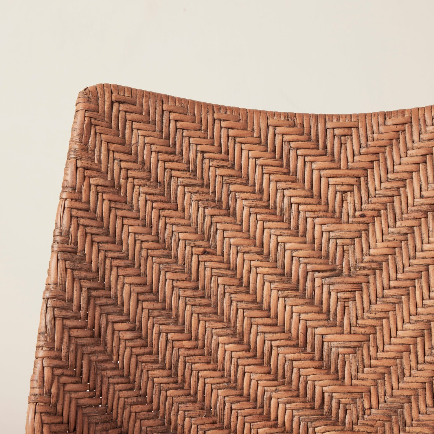 Close-up of a woven brown mat with a herringbone pattern on a light beige background- Number 5